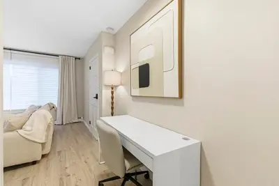 a white desk in a room with a couch and a chair at Near to Manhattan PATH Train To NYC EWR in Harrison