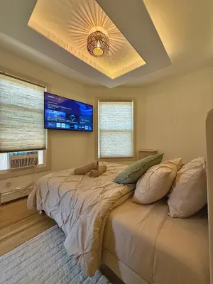 a bedroom with a large bed with a flat screen tv at Spring Rooms by Yale & Downtown in New Haven