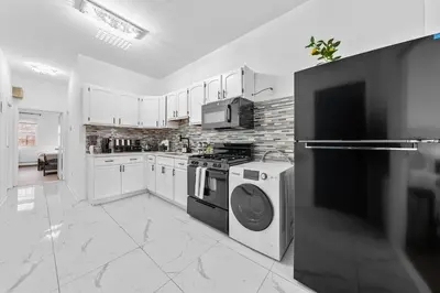 a kitchen with white cabinets and a washer and dryer at Bright 4B - Full Kitchen -15 min to Mannhatan in Jersey City