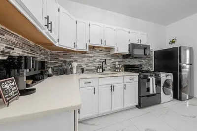 a kitchen with white cabinets and a black refrigerator at Bright 4B - Full Kitchen -15 min to Mannhatan in Jersey City