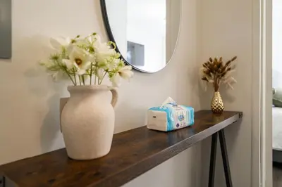 a vase with flowers on a table with a mirror at Modern 2BR Apartment - 15 min to NYC - Sleeps 6 in West New York