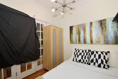 a bedroom with a bed and a painting on the wall at 10th Avenue Urban Retreat- 3BR NYC in New York