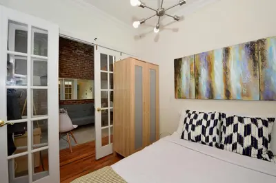 a bedroom with a bed and a painting on the wall at 10th Avenue Urban Retreat- 3BR NYC in New York