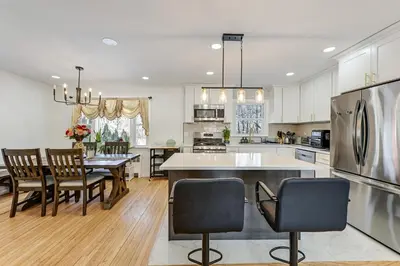 a kitchen with a table and chairs and a refrigerator at Easy Transit to NYC! Sleek North Shore Hideaway in Huntington Station
