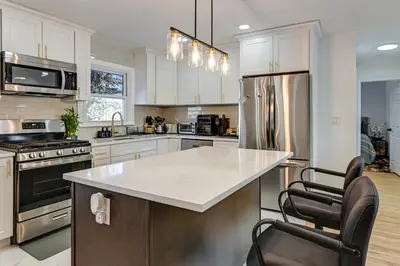 a kitchen with white cabinets and a white counter top at Easy Transit to NYC! Sleek North Shore Hideaway in Huntington Station