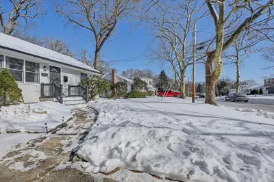 a driveway covered in snow in front of a house at Easy Transit to NYC! Sleek North Shore Hideaway in Huntington Station
