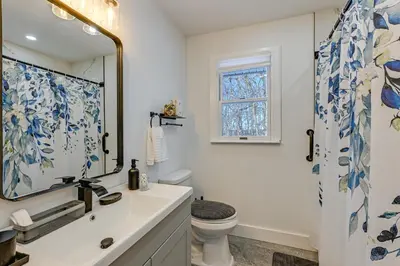 a bathroom with a sink and a toilet and a mirror at Easy Transit to NYC! Sleek North Shore Hideaway in Huntington Station