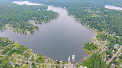 an aerial view of a river with trees and buildings at Waterfront Cottage at Highland Lake with Dock in Winsted