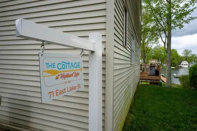 a house with a sign on the side of it at Waterfront Cottage at Highland Lake with Dock in Winsted