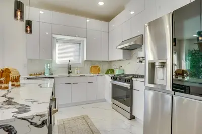 a kitchen with white cabinets and a stainless steel refrigerator at Luxe Group Getaway 6 Mi to Manhattan! in Jersey City