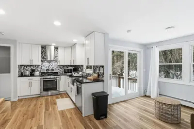 an empty kitchen with white cabinets and wooden floors at Comfortable Bloomfield 3BR Retreat home in Bloomfield