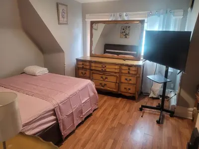 a bedroom with a bed and a dresser with a mirror at Grove#1 in Irvington