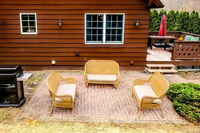 a patio with chairs and a grill and a house at Private, Family-Friendly Home Near Candlewood Lake in New Fairfield