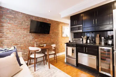 a kitchen with black cabinets and a brick wall at Urban Oasis 1BR East Village Hideaway with Patio! in New York
