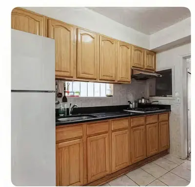 a kitchen with wooden cabinets and a white refrigerator at New York Flushing private room in Flushing