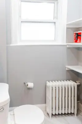 a bathroom with a toilet and a window and a radiator at Spacious 3 bedrooms Apartment-20 mins to NYC in West New York