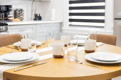 a wooden table with white plates and glasses on it at Spacious 3 bedrooms Apartment-20 mins to NYC in West New York