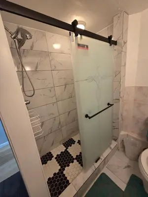 a shower with a glass door in a bathroom at Newly renovated 1 room in a 3-bedroom apartment with private toilet ands bathroom in Irvington