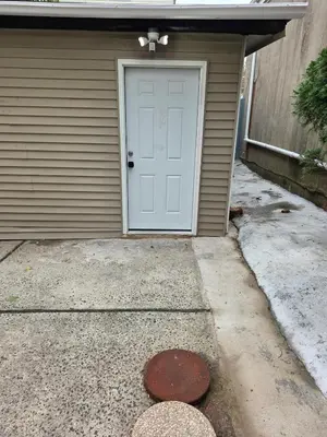 a garage with a white door and a driveway at Newly Built detached studio apartment with private toilet and bath in Irvington