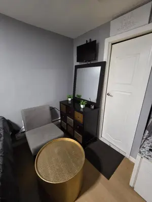 a living room with a tv and a chair and a door at Renovated Room with Private Bath in Ground Floor 3BR in Irvington