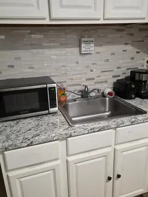 a kitchen counter with a sink and a microwave at A newly renovated room with private toilet & bathroom in a 3 bedroom apartment on the ground floor in Irvington