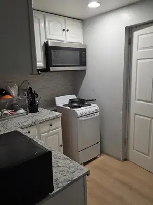 a kitchen with a stove and a microwave at A newly renovated room with private toilet & bathroom in a 3 bedroom apartment on the ground floor in Irvington