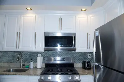 a kitchen with white cabinets and a stove and a microwave at New York private room 29 in West New York