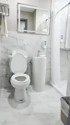 a white bathroom with a toilet and a mirror at Hotel Fuego Bronx near Yankee Stadium in Bronx