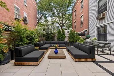 a patio with black couches and a table and chairs at Modern 2BR Brooklyn Retreat Near Manhattan with Private Backyard in Brooklyn