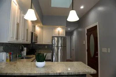 a kitchen with white cabinets and a stainless steel refrigerator at New York Private room 30 in West New York