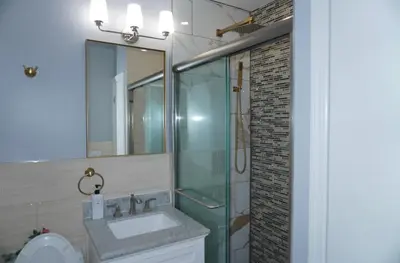 a bathroom with a sink and a glass shower at New York Private room 30 in West New York