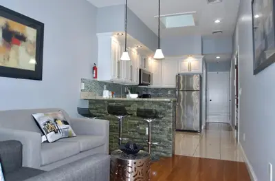 a living room with a couch and a kitchen at New York Private room 30 in West New York