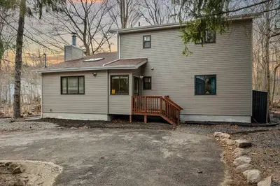 a white house with a porch and a driveway at Luxury Pocono Escape ~ Sauna | Hot Tub | Mini Golf in Tobyhanna