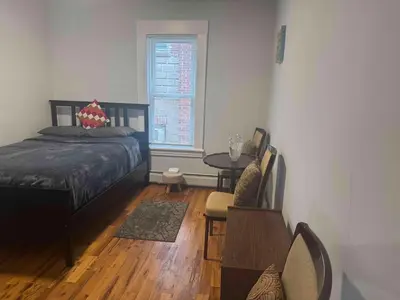 a bedroom with a bed and a table and a window at 3-bedroom peaceful apartment close to Fairfield University in Fairfield