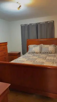 a large wooden bed in a bedroom with a window at Stratford Getaway in Stratford