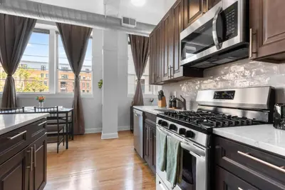a kitchen with wooden cabinets and a stove top oven at 2BR City Getaway - Close to NYC - Prime Location in Hoboken