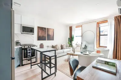 a white living room with a table and a kitchen at 319-3A XL New Modern 1BR Union Square WD in Unit in New York