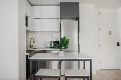 a white kitchen with a table and two stools at 317-4B Brand New Modern 1BR Union Square WD in Unit in New York