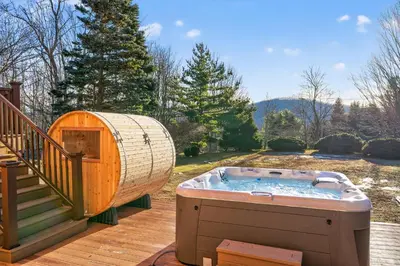 a hot tub on a deck next to a staircase at Entire Chalet in Windham NY in Maplecrest