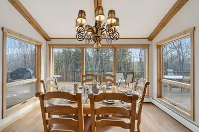 a dining room with a table and chairs and windows at Entire Chalet in Windham NY in Maplecrest