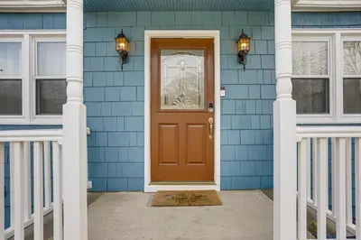 a blue house with a brown door and two windows at Walk to Lake Hopatcong Vibrant Home with Deck! in Hopatcong