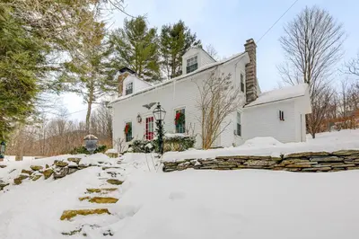 a white house with snow in front of it at Historic 1820s Homestead on Battenkill River! in Arlington