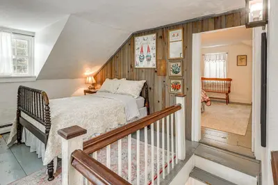 a bedroom with a bed and a staircase at Historic 1820s Homestead on Battenkill River! in Arlington