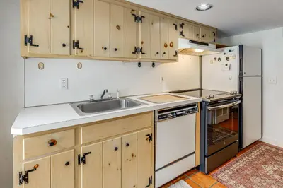a kitchen with wooden cabinets and a sink and a refrigerator at Historic 1820s Homestead on Battenkill River! in Arlington