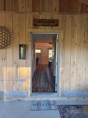 an open door to a building with a sign on the wall at Cattail Cabin in Waterville