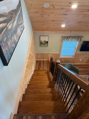 a staircase in a house with wooden floors and a painting at Cattail Cabin in Waterville