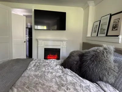 a bedroom with a bed with a fireplace and a tv at Curated Suite with Soaking Tub and Walk to Whole Foods in Jericho
