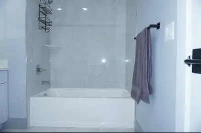 a white bathroom with a shower with a shower curtain at Big Apple room 34 in West New York