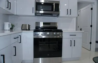 a white kitchen with a stove and a microwave at Big Apple room 34 in West New York