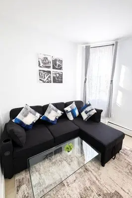 a living room with a black couch with pillows at 3BR home in Jersey city ! near metlife & NYC train in Jersey City